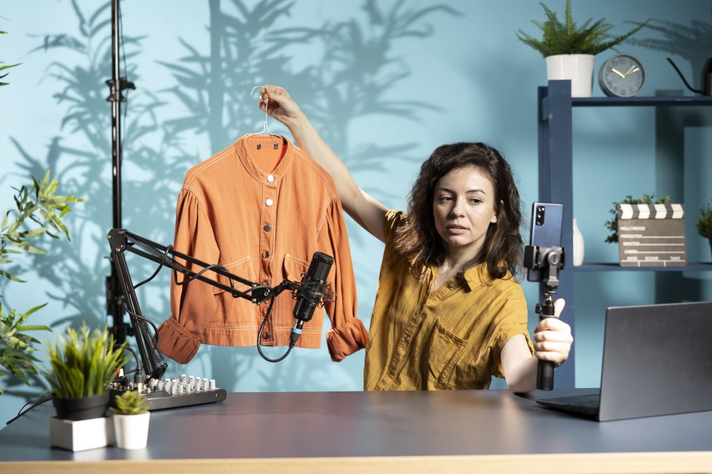 woman filming fashion vlog, holding jacket in hand